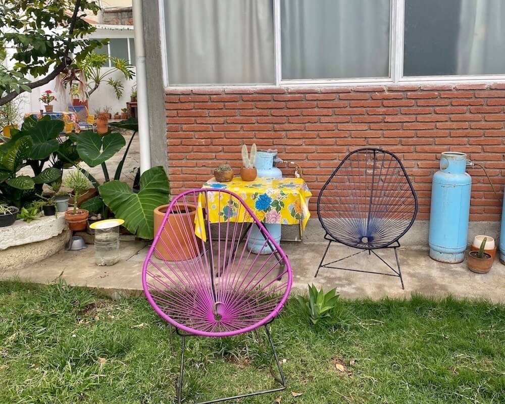 My garden with two chairs and a table with a colorful flowered tablecloth. Green grass and many plats.