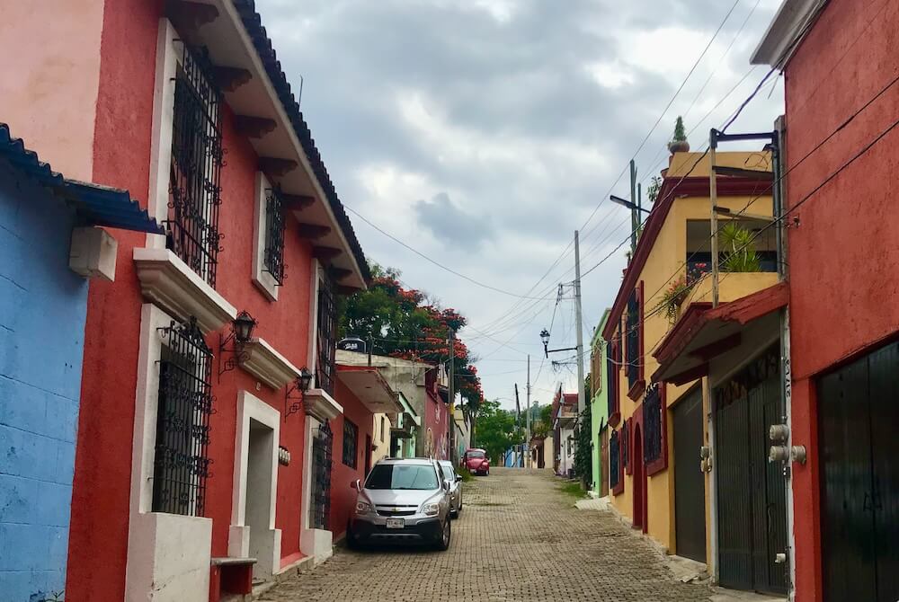 Neighborhood street with colorful homes and a cobbled street.