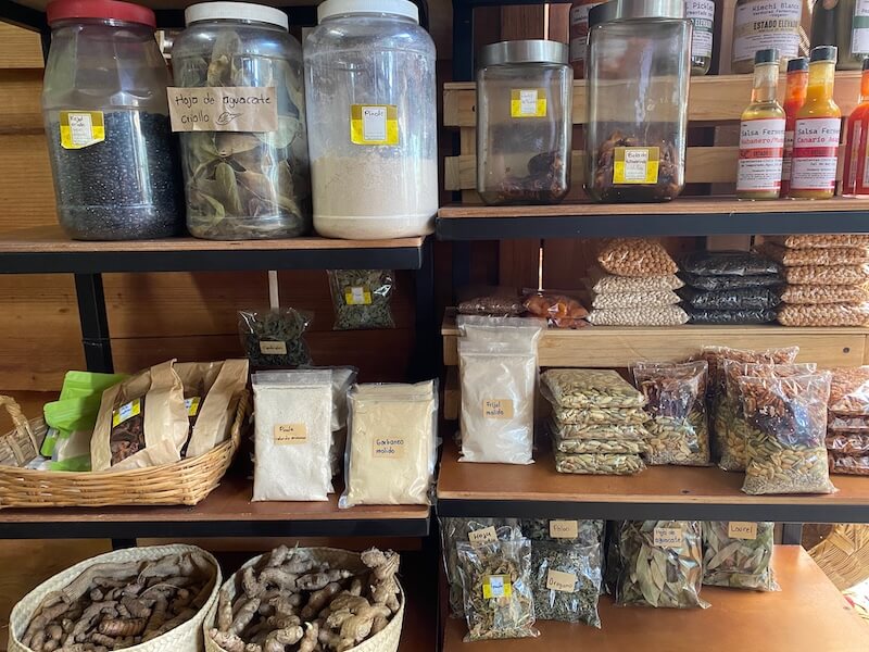 Jars, bags, and baskets full of seeds, spices and herbs on wooden shelves at La Cosecha market in Oaxaca City.