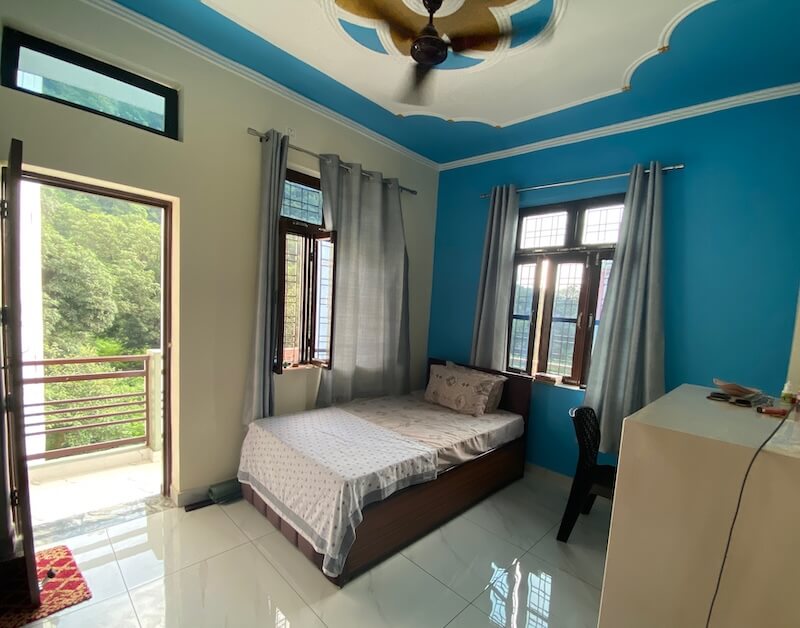 A bright clean room with balcony, a green view and lots of light and open windows.
