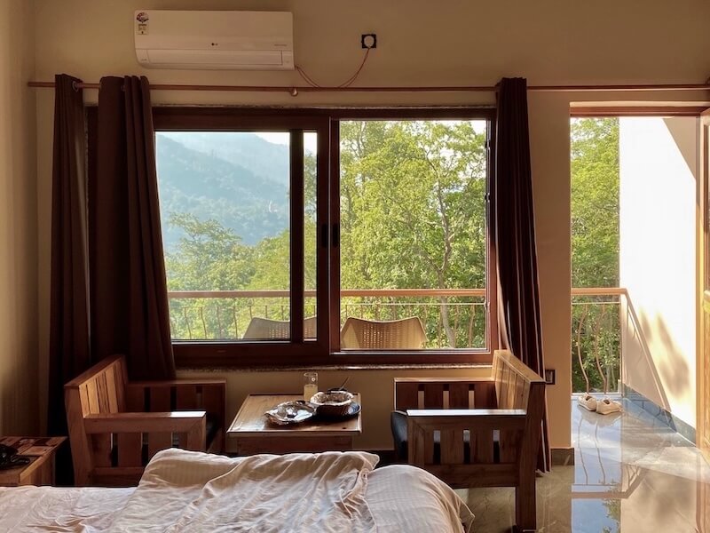 Room at sunset with natural light, 2 comfortable chair and a table and a balcony with a view of the hills.