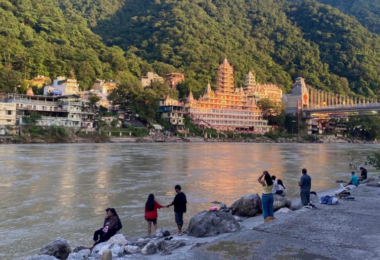 Ganga river with people relaxing and temple in the background.